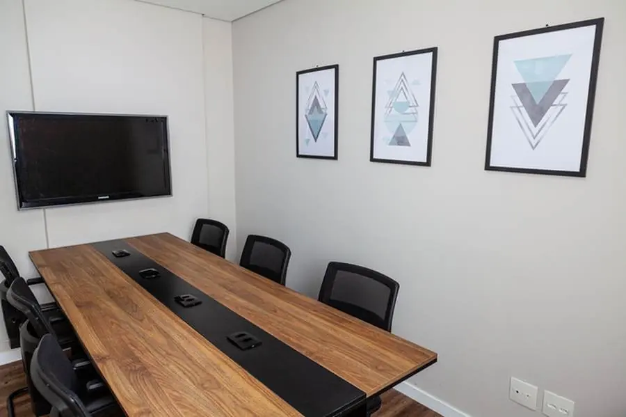 Sala de reunião com mesa de madeira e TV para apresentações