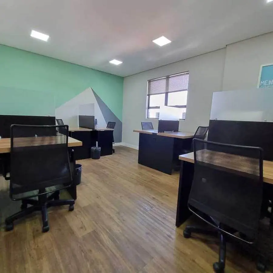 Área de coworking com mesas compartilhadas e parede grafitada