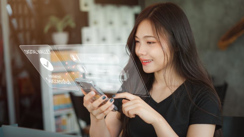Mulher com cabelos soltos mexendo em seu celular, acessando seu aplicativo bancário e realizando um pagamento