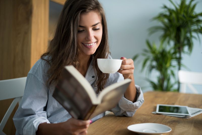 Mulher em seu escritório lendo um dos livros para melhorar a comunicação e a persuasão no trabalho.