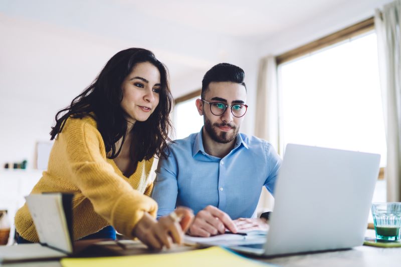 Mulher e homem analisando modelos de gestão no computador.