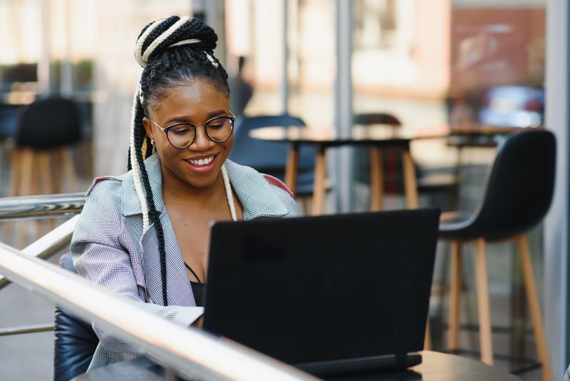 Empreendedor de sucesso​: mulher sorridente trabalhando em área comum de coworking