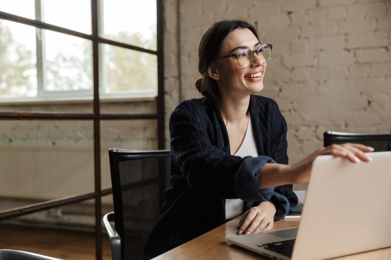 Pequenos negócios que dão lucro​: mulher sorridente em escritório de coworking.