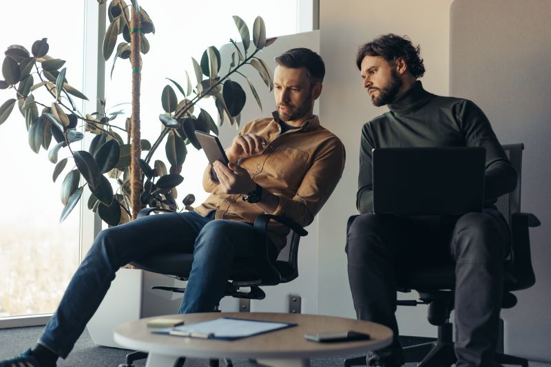 contabilidade básica: dois homens no escritório analisando informações em tablet e notebook